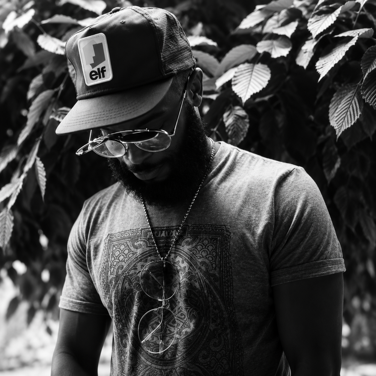 Black and white portrait of Sir Dilla beneath the leaves